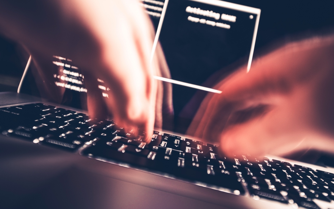 Händer skriver snabbt på laptop vid cyberattack.